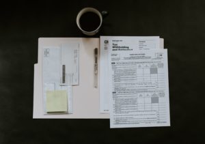 Folder with tax forms open on a table with a pen and a cup of coffee