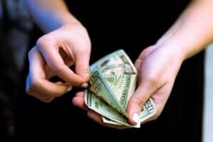Close up of a woman counting out her money in $20 bills