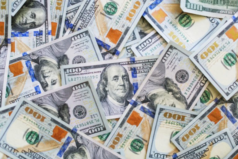 A bunch of $100 bills spread out and stacked on each other