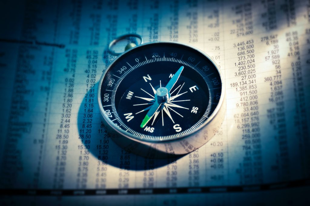 A compass pointing southwest on top of a spreadsheet full of numbers