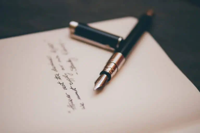An open fountain pen below a few lines of cursive text