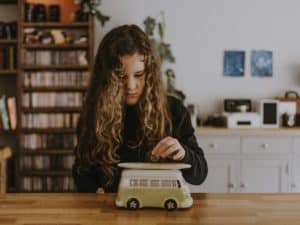 Young girl placing a coin into a Volkswagon van shaped piggy bank