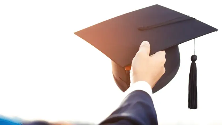 Man holding his graduation cap up in the sky