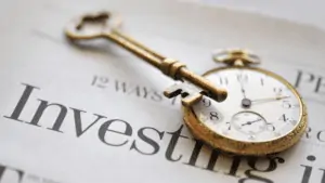 Pocket watch and antique key sitting on top of a newspaper with the title Investing